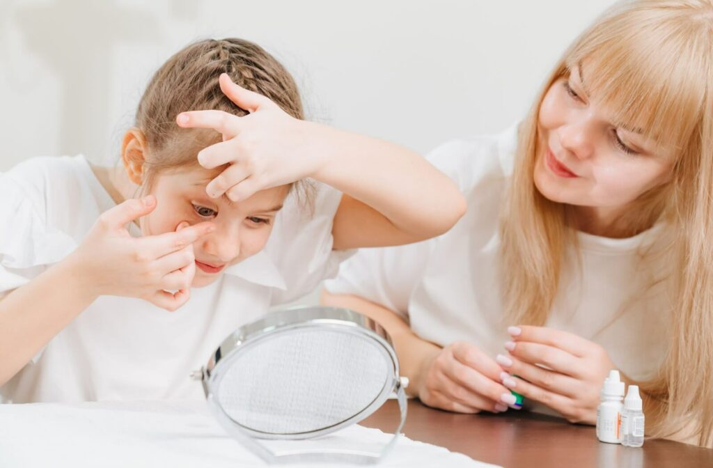 A parent supervises their child as they put in their ortho-k contact lenses.