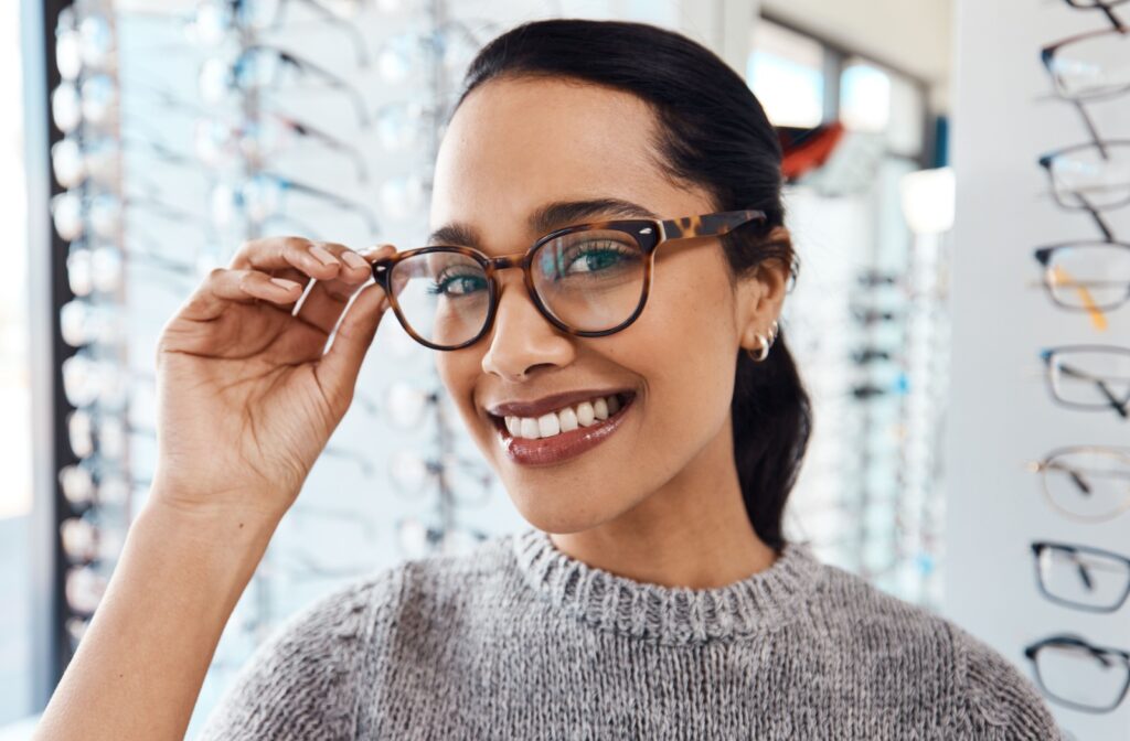 Person trying on stylish round eyeglass frames at eye clinic.